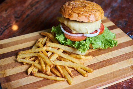Cheese burger - American cheese burger with Golden French fries on wooden boardの写真素材