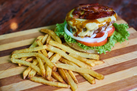 Cheese burger - American cheese burger with Golden French fries on wooden plate