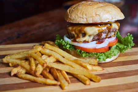 Cheese burger - American cheese burger with Golden French fries on wooden backgroundの写真素材