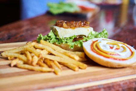 Cheese burger - American cheese burger with Golden French fries on wooden plateの写真素材
