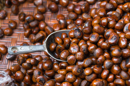 Grilled chestnuts in weave basket display for sale in a market stall.の写真素材