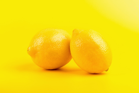 Fresh ripe lemons isolated on yellow background.の写真素材