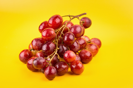 fresh and delicious red grapes isolated on yellow background.の写真素材