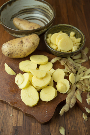 Potatoes and potato sliced on wooden table. Selective focus.の写真素材