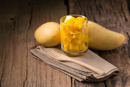 Mango fruit and mango cubes In the glass on the wooden table.の写真素材