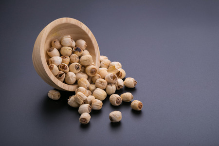 Dry lotus seeds in wooden bowl on black background.の写真素材