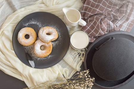 Sugary donut on a black plate and glass of milk on a dark table background. in a windows light. Breakfast concept.の写真素材