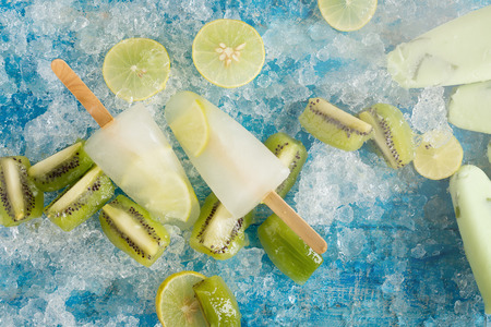 Crushed ice cubes and lemon, kiwi, homemade ice cream on vintage blue wooden table. Top view.の写真素材