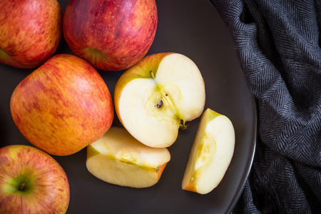 Red apples in a black bowl on a Black fabric background.の写真素材