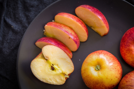 Red apples in a black bowl on a Black fabric background.の写真素材