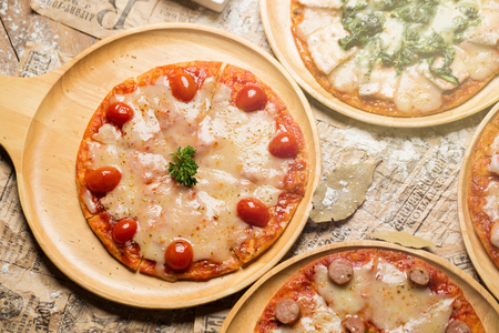 Fresh delicious Italian pizza with mushrooms on thin crust, on a wooden serving plate.の写真素材