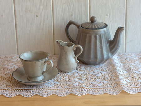 Tea set is Gray on a wooden background. Teapot, creamer, Cup and saucer on the table. Ceramic kitchenware.の写真素材