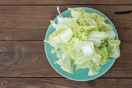 Heap of chopped lettuce In a blue plate on a wooden background.の写真素材
