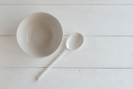 white bowl and spoon ceramic on a white wooden background.の写真素材