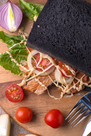 Pounded pork jerky and Vegetable in Charcoal bread Sandwich on wooden background.の写真素材