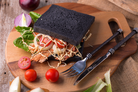 Pounded pork jerky and Vegetable in Charcoal bread Sandwich on wooden background.の写真素材