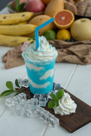 Mint and yoghurt Smoothies on a wooden plate with ice cubes and fruit as background.の写真素材