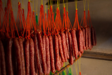 Fresh and dried Chinese sausages hang from racks.の写真素材