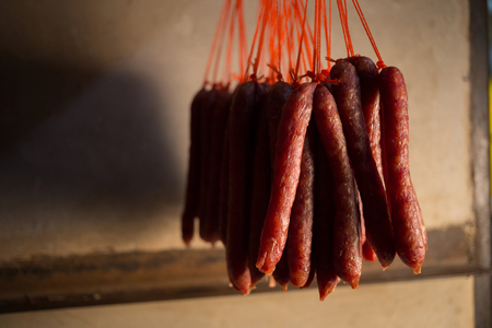 Fresh and dried Chinese sausages hang from racks.の写真素材