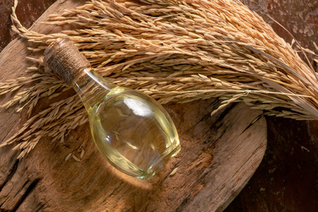 Bottle of rice bran oil and unmilled rice on wooden background.の写真素材