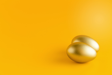 Golden egg on a yellow background. copy space.の写真素材