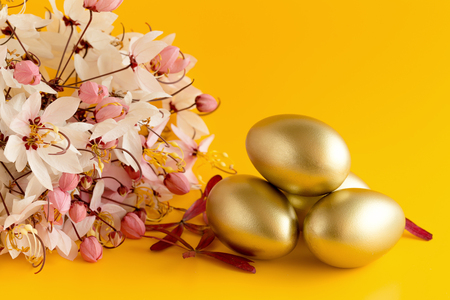 White, pink flowers and Golden egg on a yellow background.の写真素材