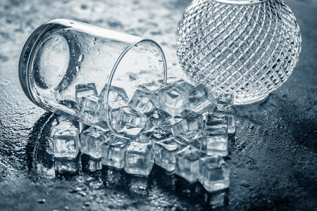 Glass of Ice cube on wooden table and light blurred background.の写真素材