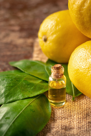 Bottles with Essential Oil of Lemon peel and leaf on wooden table.の写真素材