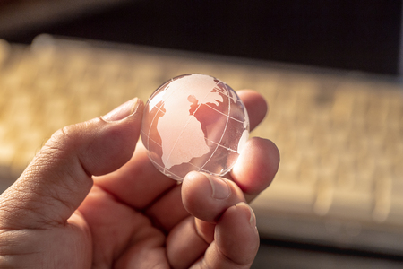 Globe is made of glass on hand in dark background.の写真素材