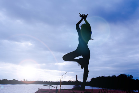 Yoga in silhouette with dramatic sunset sky background.の写真素材