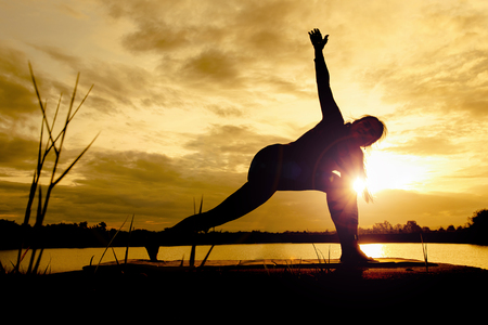 Yoga in silhouette with dramatic sunset sky background.の写真素材