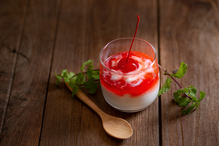 Glass of Cherry yogurt on a brown wood table.の写真素材