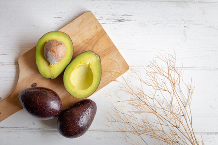 Fresh organic avocado sliced in half on white wooden table.の写真素材