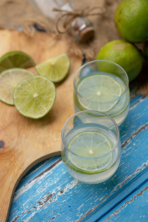 Lime juice and lemon on a blue wooden table.の写真素材