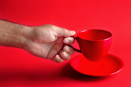 hand holding a Red coffee cup on a red background.の写真素材