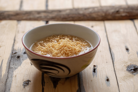 Noodles in bowl on wooden background, selective focus.の写真素材