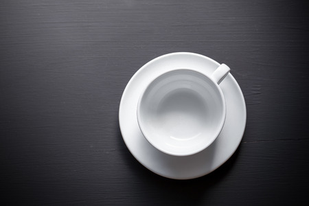 Empty white ceramic coffee mug on a black background.