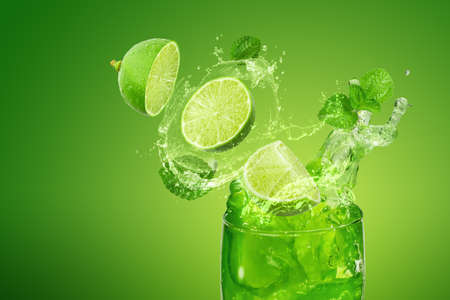 Lemon juice splashing isolated on a green background with mint leaves.