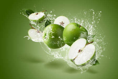 Water Splashing on Green apple with green leaf and cut slice with seed on green background.の写真素材