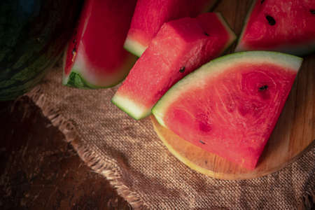 watermelon and watermelon pieces in a wooden background.