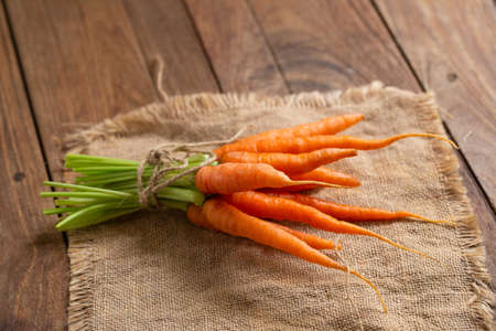Fresh baby carrots on wooden cutting board and wooden background.の写真素材