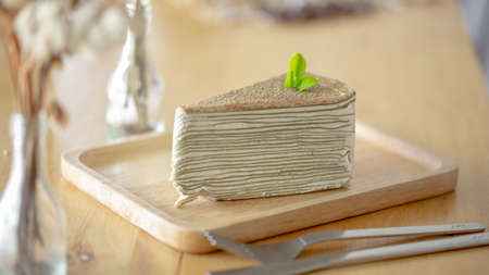 Green tea crepe cake with green tea leaf on wooden plate.の写真素材