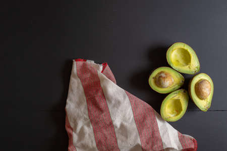 Fresh organic avocado sliced in half on black wooden table.の写真素材