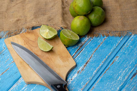 Lime juice and lemon on a blue wooden table.