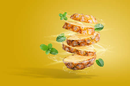 Water Splashing on Split Pineapple Fruit isolated over yellow backgroundの写真素材