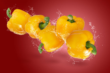 Creative layout made from yellow Bell Pepper and water splashing on a red backgroundの写真素材