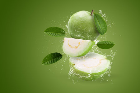 Creative layout made form whole and slice of Guava fruit and water splashing on a green background.の写真素材