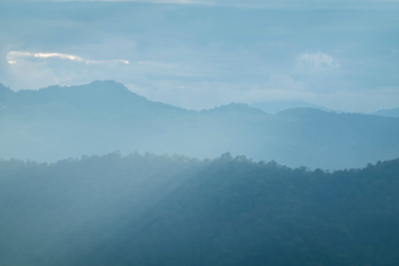 Sun rays filter through the clouds in hills of the valley illuminated by the sun's rays filtering...
