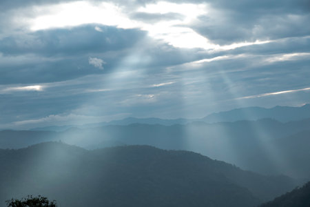 Sun rays filter through the clouds in hills of the valley illuminated by the sun's rays filtering through the cloudsの写真素材