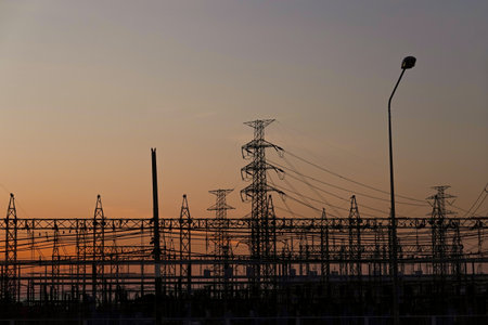 Silhouetted high-voltage electric tower in the dramatic sunset sky